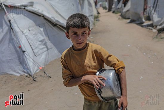 طفل فلسطيني نازح داخليًا ينتظر استلام حصة طعام من مطبخ خيري طفل فلسطيني نازح داخليًا ينتظر استلام حصة طعام من مطبخ خيري