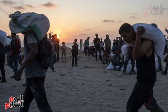 الفلسطنيين يحملون المساعدات الفلسطنيين يحملون المساعدات