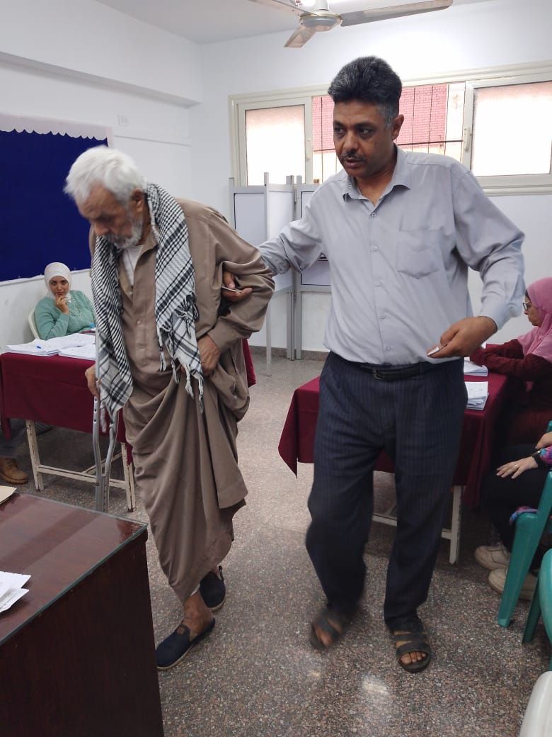 موظف يساعد مسن داخل لجنة فرعية بالمطرية