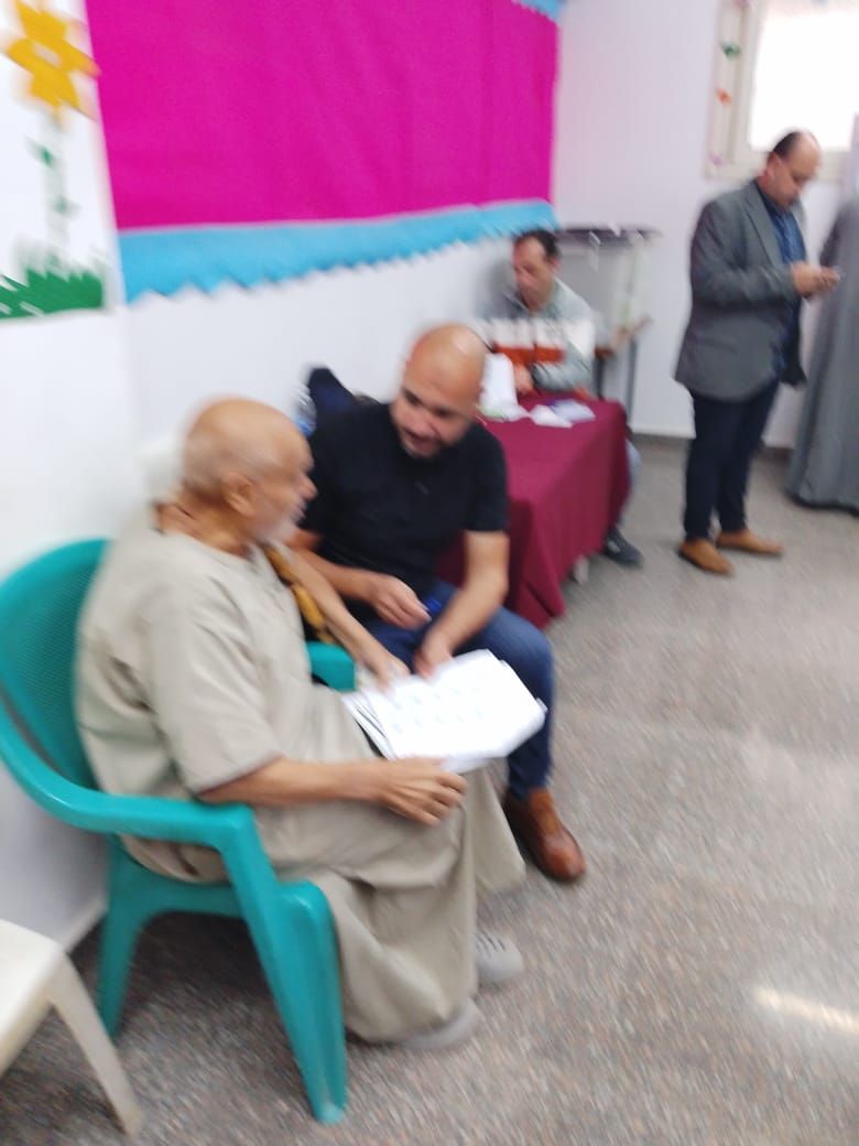 ناخب مسن يجلس للتوقيع على كشف الحضور في لجنة الانتخابات ناخب مسن يجلس للتوقيع على كشف الحضور في لجنة الانتخابات