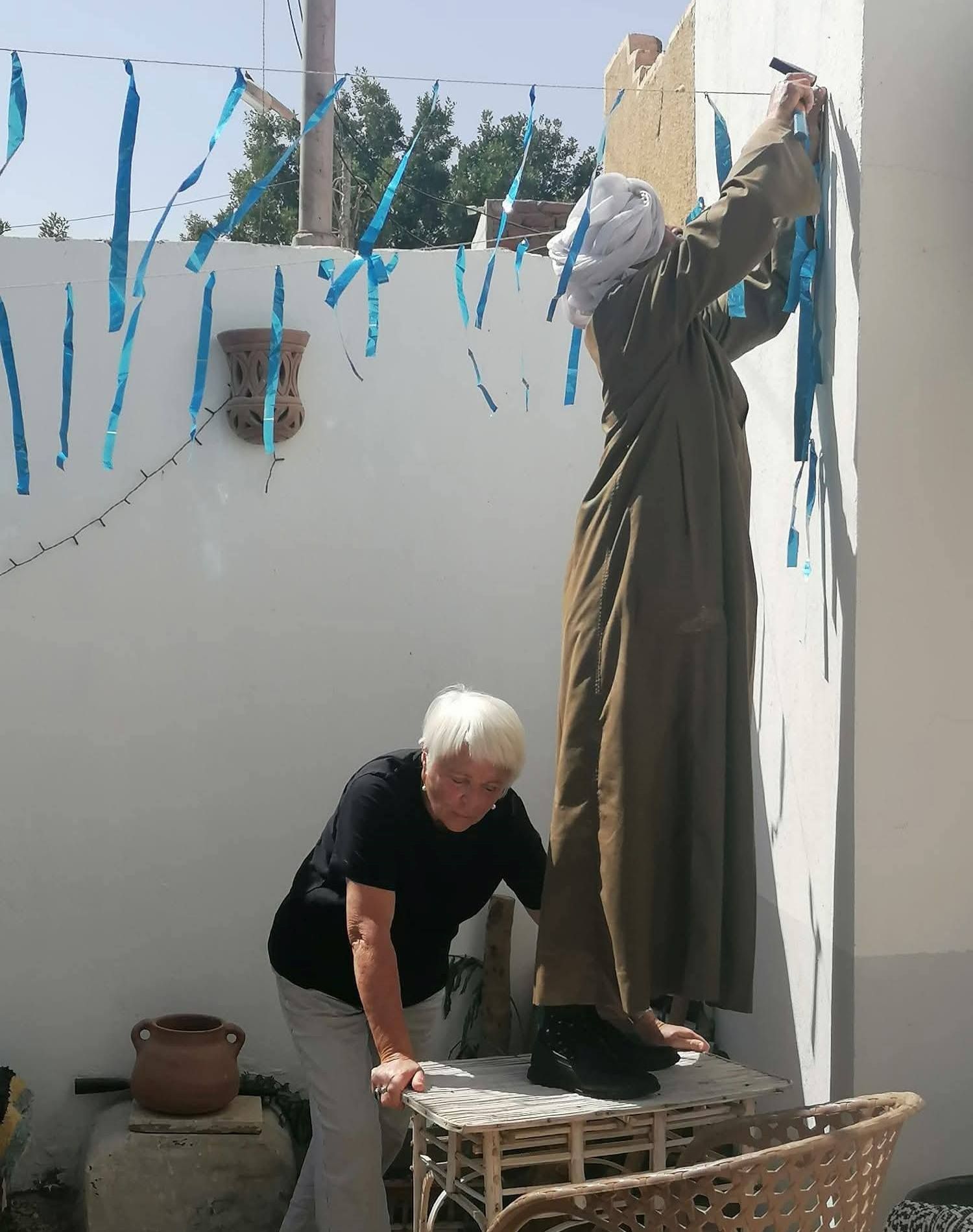 عامل يساعد السائحة البلجيكية فى تعليق زينة رمضان عامل يساعد السائحة البلجيكية فى تعليق زينة رمضان