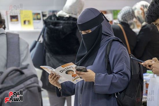 سيدة تتفقد القصص والكتب داخل المعرض سيدة تتفقد القصص والكتب داخل المعرض