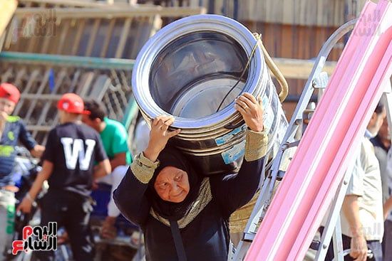 سيدة تحمل غسالة بعد شرائها من الخردة سيدة تحمل غسالة بعد شرائها من الخردة