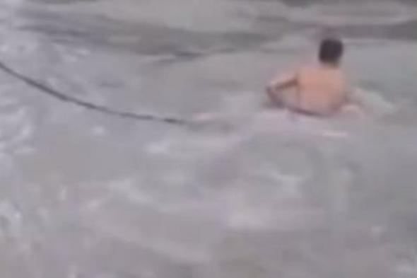 رجل شرطة صينى يقوم بعمل بطولى وينقذ شخص جرفته السيول.. فيديو